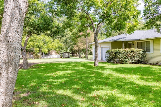 view of yard featuring driveway, an attached garage, and a storage unit