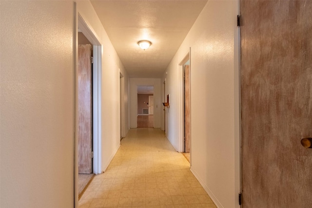 hallway featuring light floors, visible vents, and baseboards