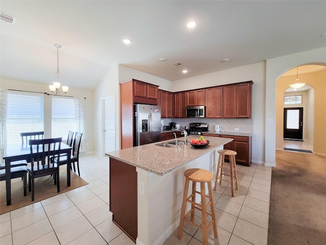 kitchen with arched walkways, stainless steel appliances, a sink, visible vents, and a kitchen bar