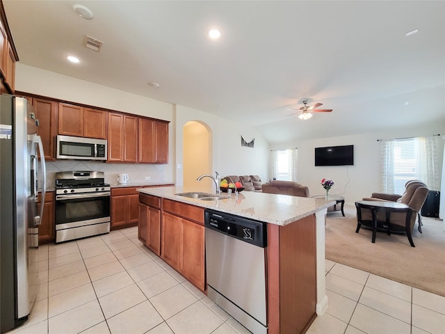 kitchen with light tile patterned floors, light colored carpet, open floor plan, stainless steel appliances, and a sink