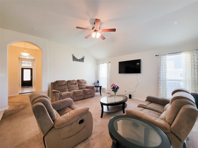 living area featuring arched walkways, lofted ceiling, light carpet, a ceiling fan, and baseboards