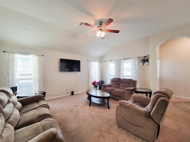 living area featuring arched walkways, light colored carpet, lofted ceiling, and baseboards