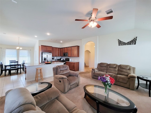 living room featuring arched walkways, recessed lighting, visible vents, light tile patterned flooring, and ceiling fan with notable chandelier