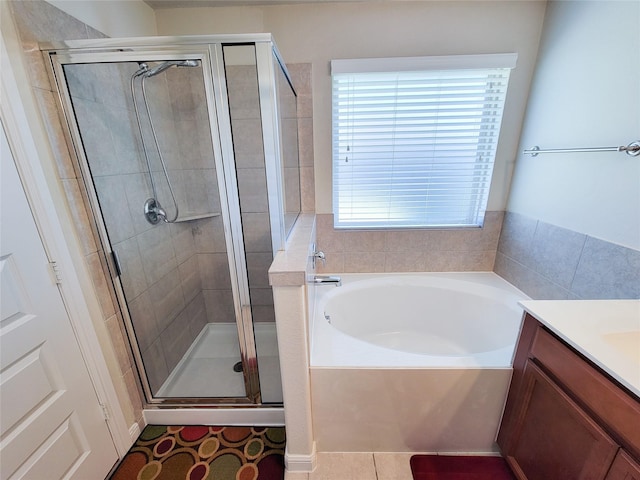 bathroom with a stall shower, tile patterned flooring, a garden tub, and vanity