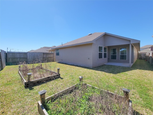 back of property with a yard, a fenced backyard, and a vegetable garden