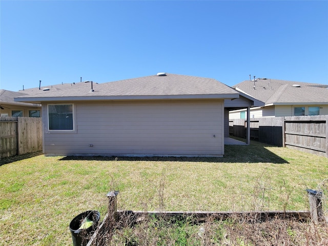 back of house with a fenced backyard and a yard