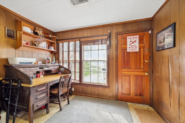 office space with wooden walls, baseboards, visible vents, light colored carpet, and ornamental molding