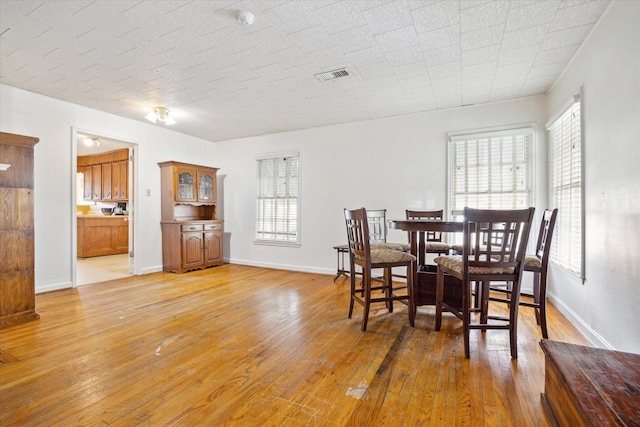 dining area with light wood finished floors, visible vents, and baseboards