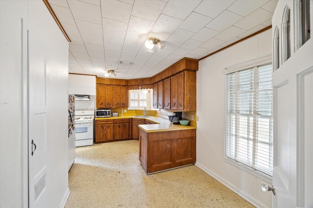 kitchen featuring visible vents, stainless steel microwave, brown cabinets, gas range gas stove, and a sink