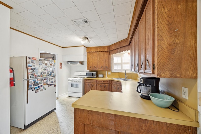 kitchen with white appliances, a sink, visible vents, range hood, and brown cabinets