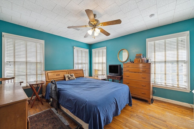 bedroom featuring ceiling fan, baseboards, and wood finished floors