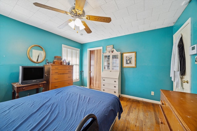 bedroom with ceiling fan, baseboards, and wood finished floors