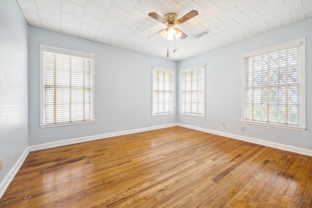 empty room featuring baseboards, hardwood / wood-style flooring, visible vents, and a healthy amount of sunlight