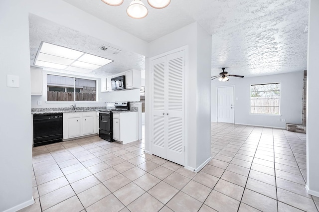 kitchen with a textured ceiling, light tile patterned flooring, white cabinets, open floor plan, and black appliances