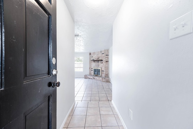 corridor featuring a textured ceiling, baseboards, and light tile patterned floors