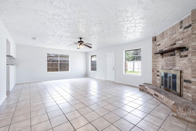 unfurnished living room featuring light tile patterned floors, a fireplace, a ceiling fan, and a textured ceiling