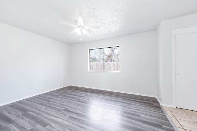 unfurnished room featuring a ceiling fan, a textured ceiling, baseboards, and wood finished floors