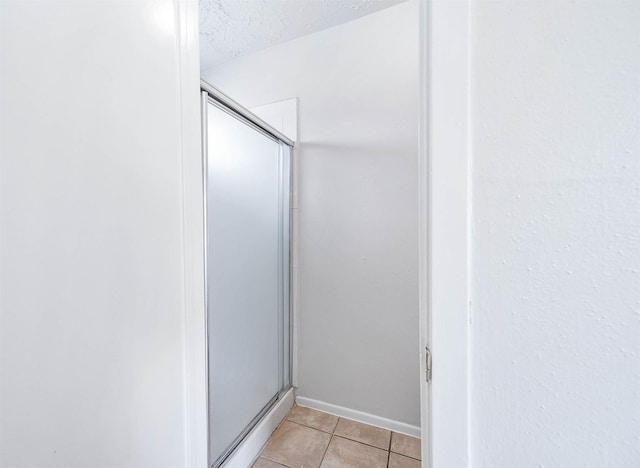 bathroom with a shower stall, a textured ceiling, and tile patterned floors