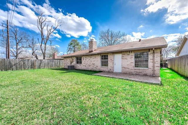 rear view of house featuring a patio, a fenced backyard, brick siding, a yard, and a chimney