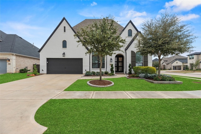 french country inspired facade with a front yard, concrete driveway, and an attached garage