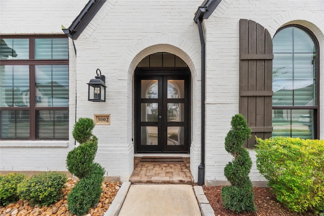 doorway to property featuring french doors and brick siding