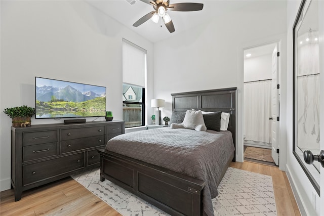 bedroom with light wood-style floors, a ceiling fan, and ensuite bathroom