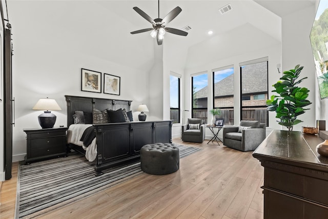 bedroom with baseboards, visible vents, a towering ceiling, and light wood finished floors