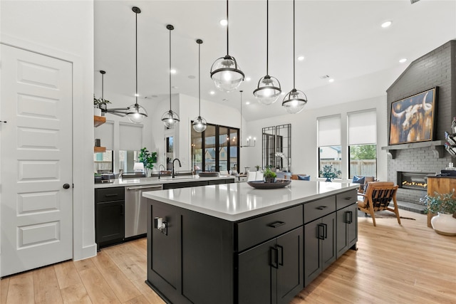 kitchen featuring a fireplace, light countertops, light wood-style floors, a kitchen island, and dishwasher