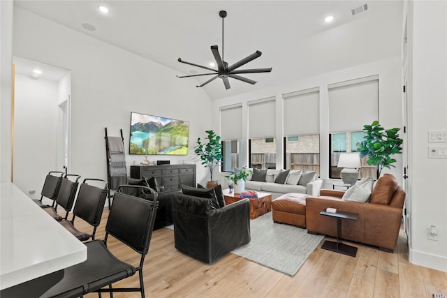 living area featuring lofted ceiling, visible vents, light wood-style flooring, and recessed lighting