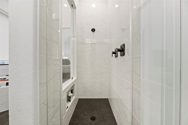 bathroom with a textured wall and tiled shower