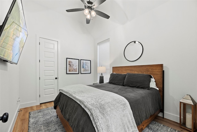 bedroom with lofted ceiling, light wood-style floors, baseboards, and a ceiling fan