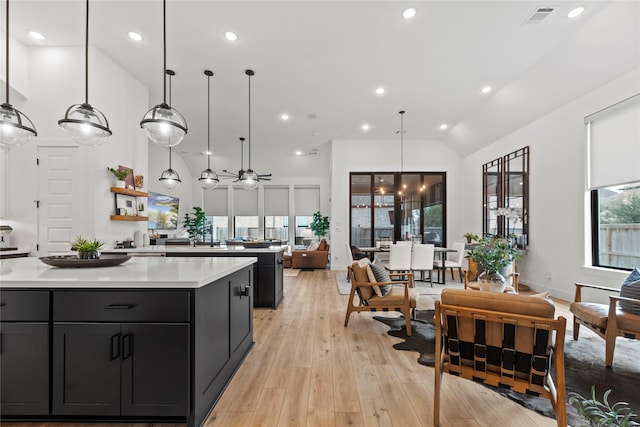 kitchen with lofted ceiling, dark cabinets, a center island, light countertops, and light wood-style floors