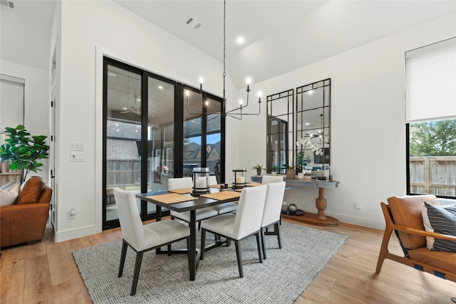 dining area with a towering ceiling, wood finished floors, visible vents, and baseboards