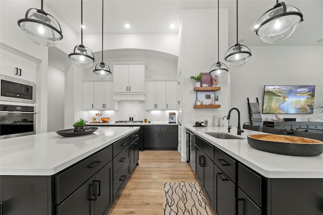 kitchen featuring appliances with stainless steel finishes, white cabinetry, a sink, and decorative backsplash