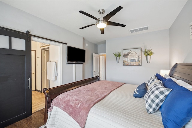 bedroom featuring a barn door, visible vents, and a ceiling fan