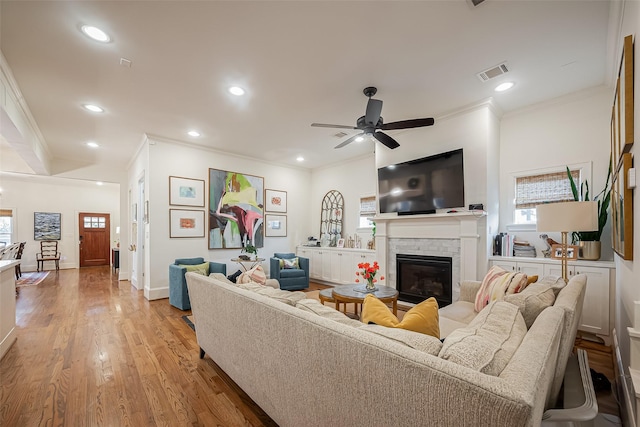 living room featuring light wood-type flooring, visible vents, a ceiling fan, a glass covered fireplace, and recessed lighting