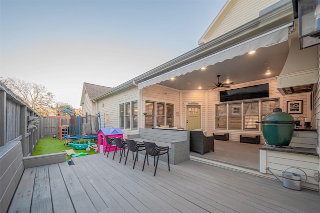 wooden terrace with a fenced backyard and a trampoline