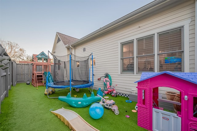 exterior space with a trampoline, a fenced backyard, and a lawn