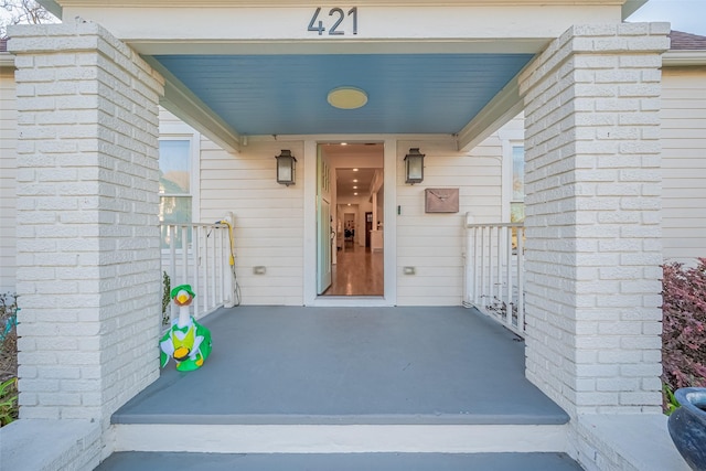 view of exterior entry featuring brick siding and a porch