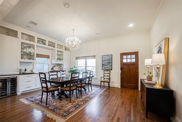 dining area featuring an inviting chandelier, beverage cooler, dark wood-style flooring, and ornamental molding