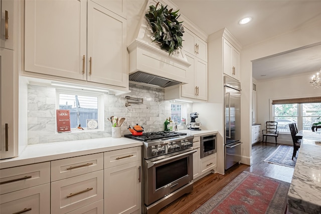 kitchen featuring backsplash, dark wood-type flooring, ornamental molding, white cabinetry, and high end appliances