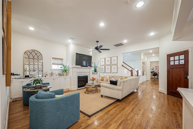 living room with visible vents, a glass covered fireplace, and light wood finished floors