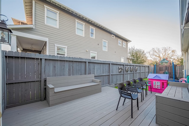 wooden deck with a trampoline and a fenced backyard