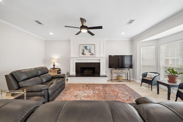 living room featuring a large fireplace, visible vents, light wood-style floors, and crown molding