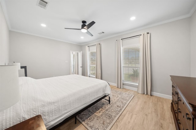 bedroom with crown molding, light wood-style floors, visible vents, and baseboards