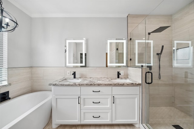 bathroom featuring double vanity, a freestanding tub, a shower stall, and a sink