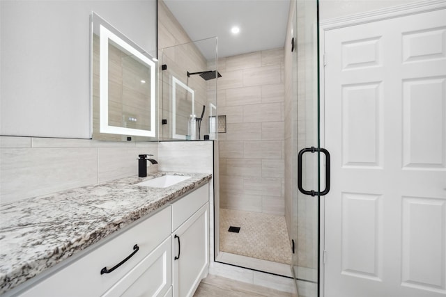 bathroom featuring a shower stall, decorative backsplash, and vanity