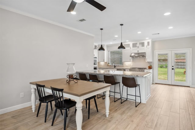 dining area featuring french doors, crown molding, light wood finished floors, visible vents, and baseboards