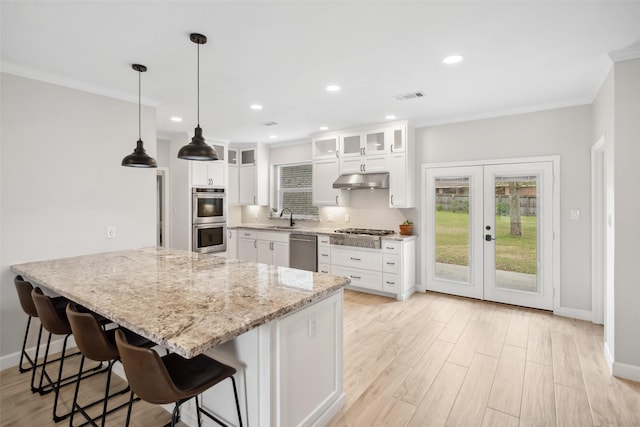 kitchen featuring visible vents, appliances with stainless steel finishes, a sink, under cabinet range hood, and a kitchen breakfast bar