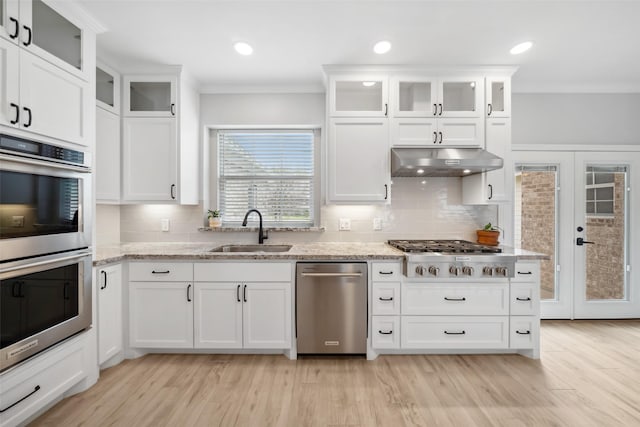 kitchen with white cabinets, ornamental molding, stainless steel appliances, under cabinet range hood, and a sink